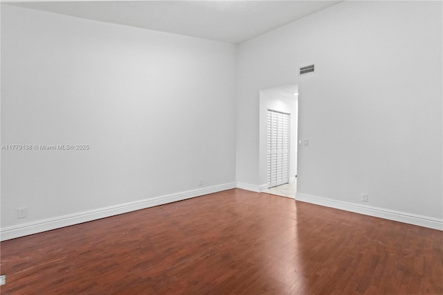 empty room with baseboards, wood finished floors, and visible vents