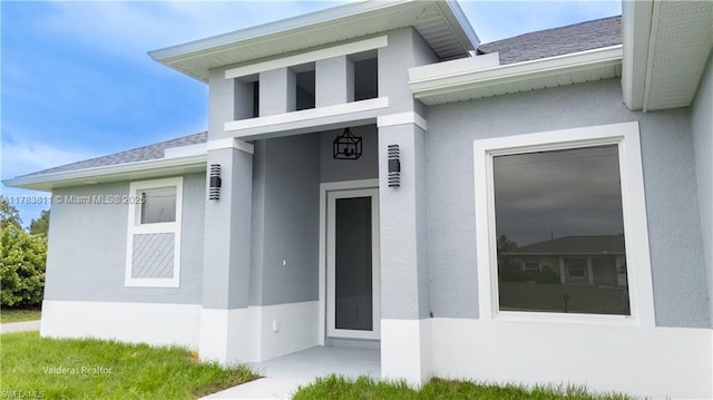 2901 27th St SW, Lehigh Acres, FL 33976 - doorway to property featuring stucco siding and a shingled roof