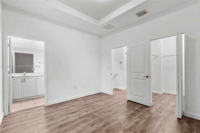 340 NE 208th Ter, Miami, FL 33179 - unfurnished bedroom with a tray ceiling, light wood finished floors, a spacious closet, and visible vents