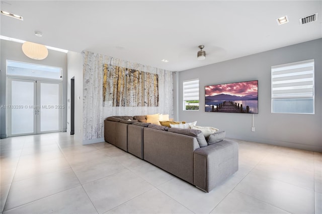 living room with an accent wall, visible vents, light tile patterned flooring, french doors, and baseboards