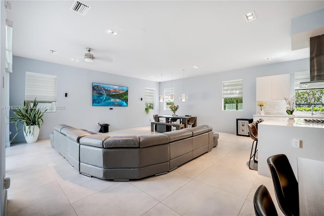 living area with visible vents, a wealth of natural light, ceiling fan, and light tile patterned floors