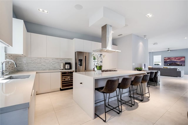 kitchen featuring stainless steel refrigerator with ice dispenser, a sink, wine cooler, island exhaust hood, and a kitchen island