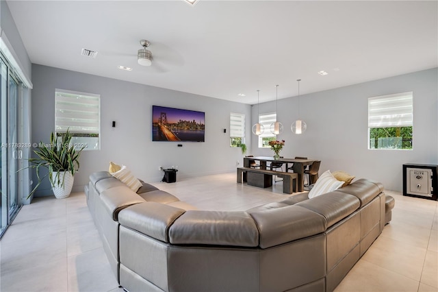 living room featuring a healthy amount of sunlight, light tile patterned floors, visible vents, and ceiling fan