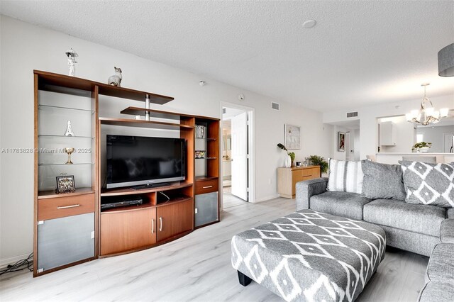 7751 Southampton Ter Unit 216, Tamarac, FL 33321 - living room featuring light wood finished floors, a chandelier, and a textured ceiling