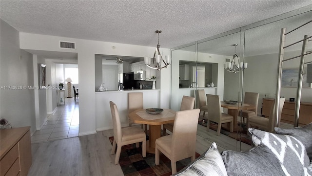 7751 Southampton Ter Unit 216, Tamarac, FL 33321 - dining room featuring a chandelier, light wood-style flooring, a textured ceiling, and ceiling fan