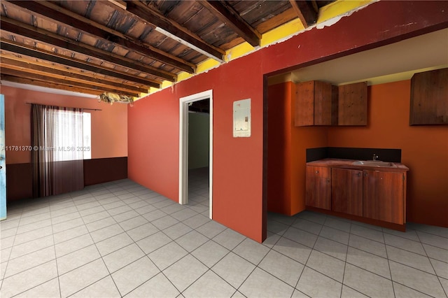 empty room with a sink, beamed ceiling, light tile patterned floors, and wood ceiling