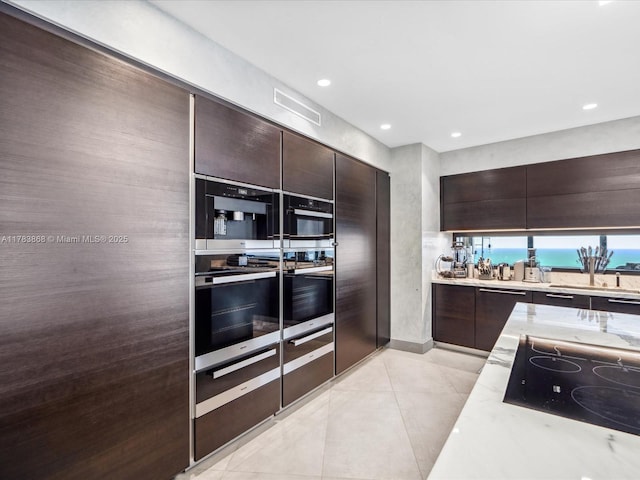 18555 Collins Ave Unit 5505, Sunny Isles Beach, FL 33160 - kitchen featuring appliances with stainless steel finishes, dark brown cabinets, light tile patterned flooring, modern cabinets, and recessed lighting