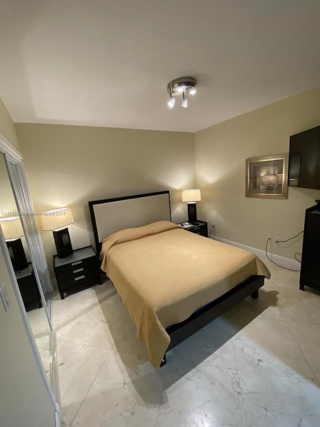 bedroom featuring marble finish floor and baseboards