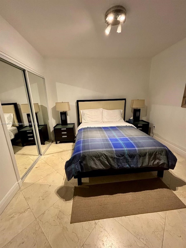 bedroom with a closet, marble finish floor, and baseboards