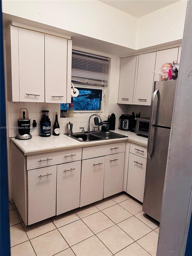 4371 SW 14th St, Miami, FL 33134 - kitchen featuring freestanding refrigerator, light tile patterned floors, white cabinetry, light countertops, and a sink