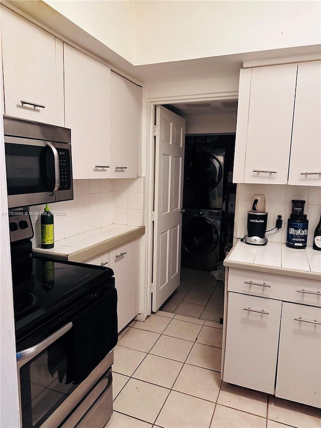 4371 SW 14th St, Miami, FL 33134 - kitchen featuring tile counters, backsplash, white cabinets, stacked washer / drying machine, and stainless steel appliances
