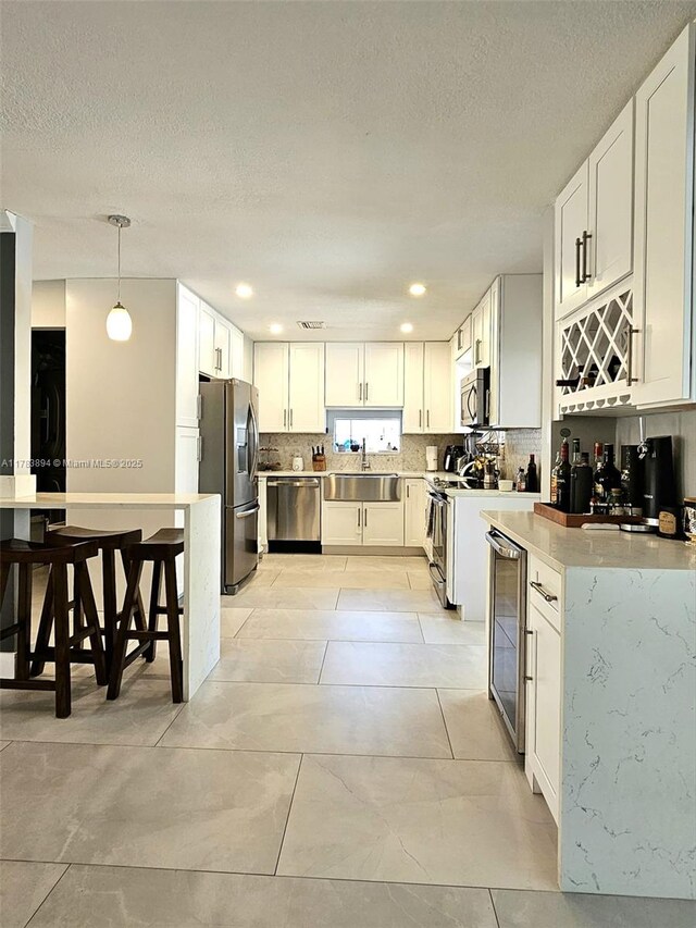 3602 NE 18th Ave, Oakland Park, FL 33334 - kitchen with tasteful backsplash, a textured ceiling, stainless steel appliances, beverage cooler, and a sink
