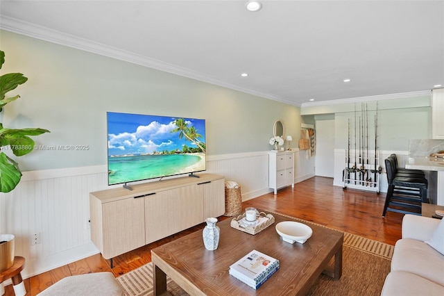 living area featuring ornamental molding, wainscoting, and wood finished floors