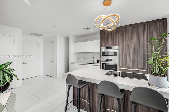 kitchen with a chandelier, visible vents, modern cabinets, double oven, and a sink