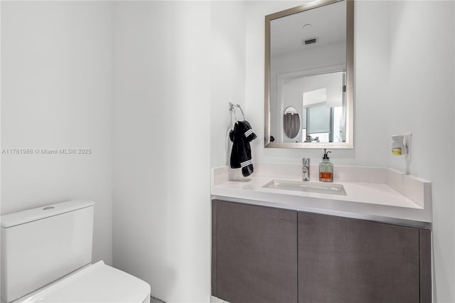 half bathroom featuring toilet, vanity, and visible vents