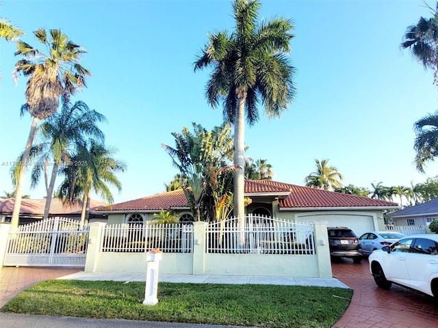 view of front of property with a fenced front yard, stucco siding, decorative driveway, a tile roof, and a garage