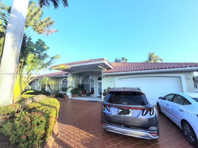 view of front facade featuring driveway, a tile roof, a garage, and stucco siding