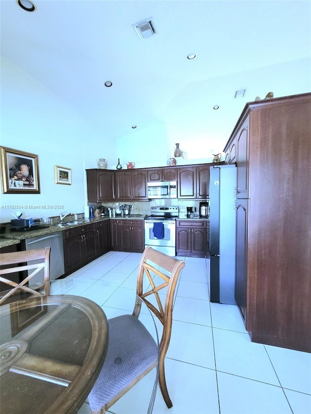 kitchen featuring visible vents, dark countertops, dark brown cabinetry, stainless steel appliances, and light tile patterned flooring