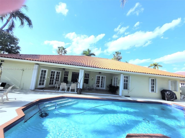 back of house featuring french doors, a tiled roof, a ceiling fan, and stucco siding