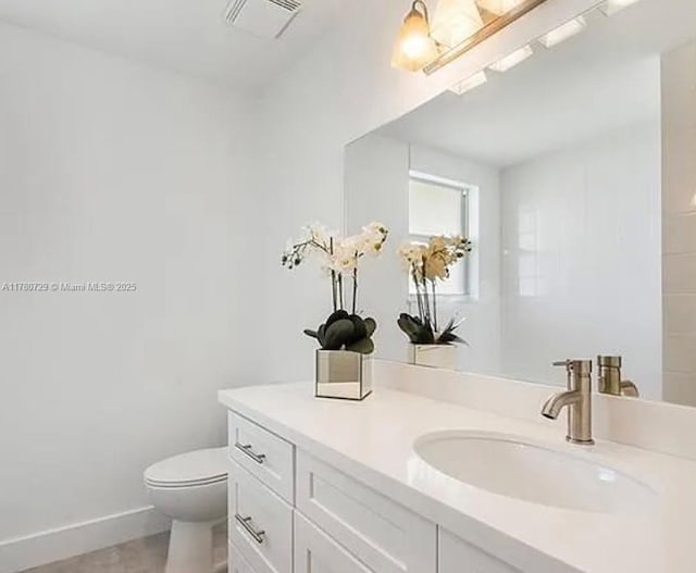 bathroom featuring visible vents, toilet, vanity, and baseboards
