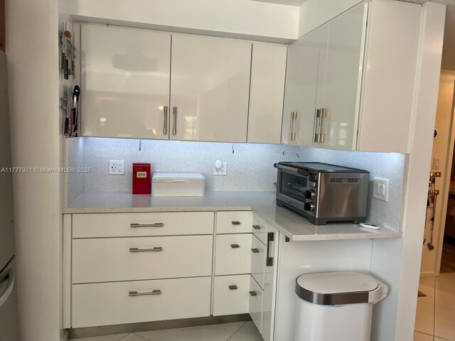 interior space with light tile patterned floors, white cabinetry, and a toaster