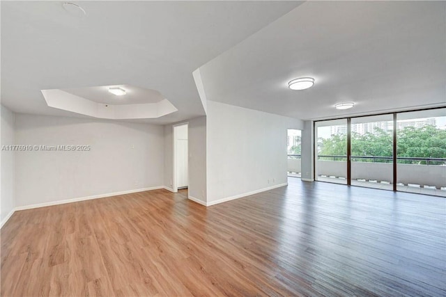 19667 Turnberry Way Unit 3F, Aventura, FL 33180 - unfurnished room featuring baseboards, wood finished floors, expansive windows, and a tray ceiling