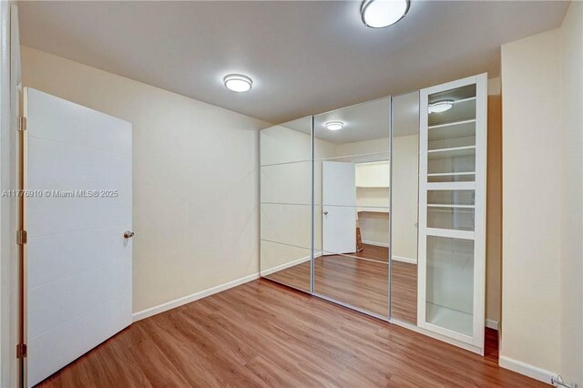 19667 Turnberry Way Unit 3F, Aventura, FL 33180 - unfurnished bedroom with wood finished floors, baseboards, and a closet