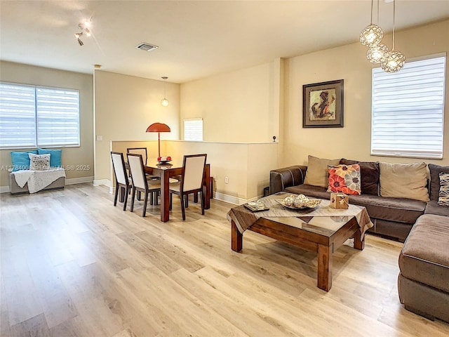 living area with light wood finished floors, baseboards, and visible vents