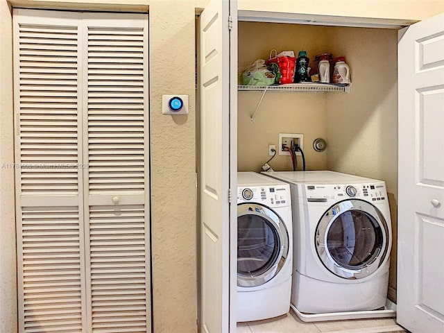 clothes washing area featuring a textured wall, a heating unit, separate washer and dryer, and laundry area