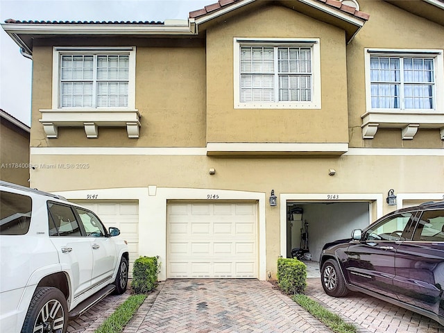 exterior space with driveway, a garage, and stucco siding