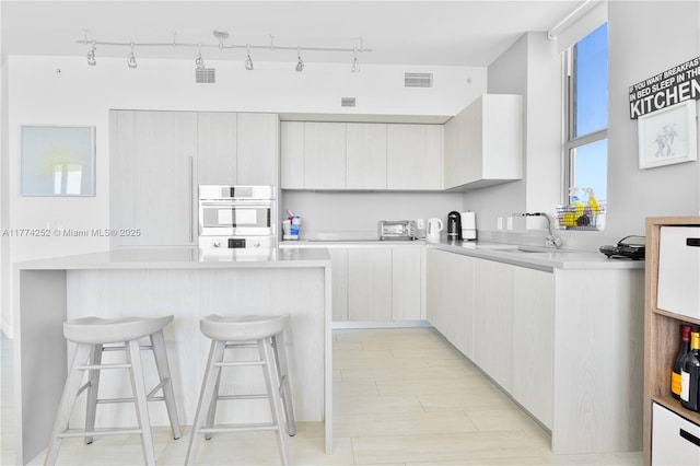 4010 S Ocean Dr Unit T3609, Hollywood, FL 33019 - kitchen featuring a kitchen breakfast bar, a sink, stainless steel oven, light countertops, and visible vents