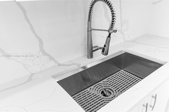 room details featuring light stone countertops, white cabinetry, and a sink