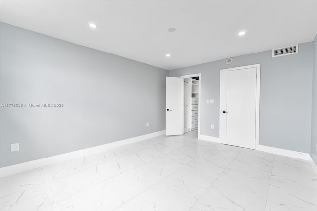 empty room with marble finish floor, baseboards, and recessed lighting