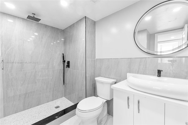 full bathroom featuring toilet, tile walls, a walk in shower, and vanity