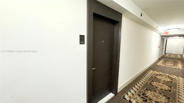 hall featuring elevator, baseboards, and carpet flooring