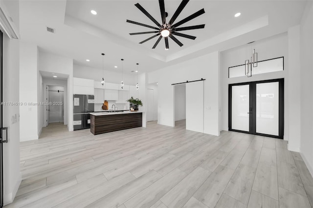 2138 SW 3rd Ave, Cape Coral, FL 33991 - living area with a tray ceiling, a barn door, recessed lighting, a high ceiling, and light wood-style flooring