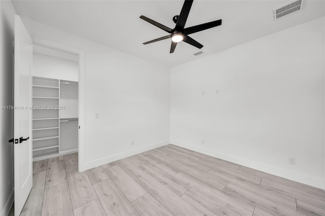 2138 SW 3rd Ave, Cape Coral, FL 33991 - unfurnished bedroom featuring wood finished floors, a walk in closet, a closet, and a ceiling fan