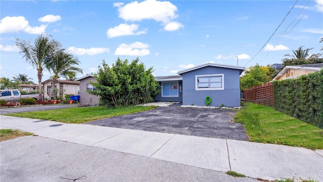 single story home featuring brick siding, driveway, and fence