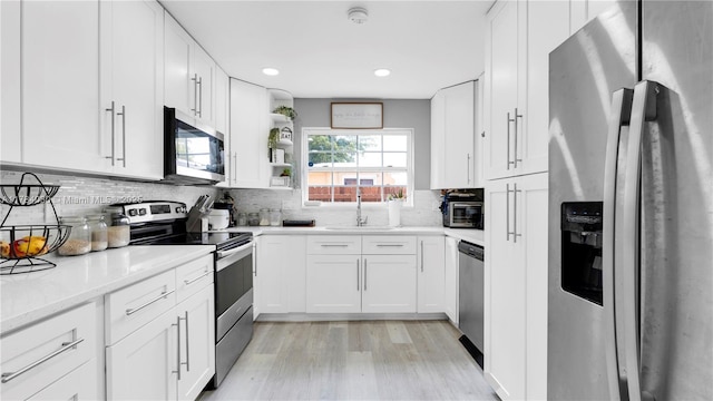 kitchen with white cabinetry, light wood-type flooring, stainless steel appliances, and decorative backsplash