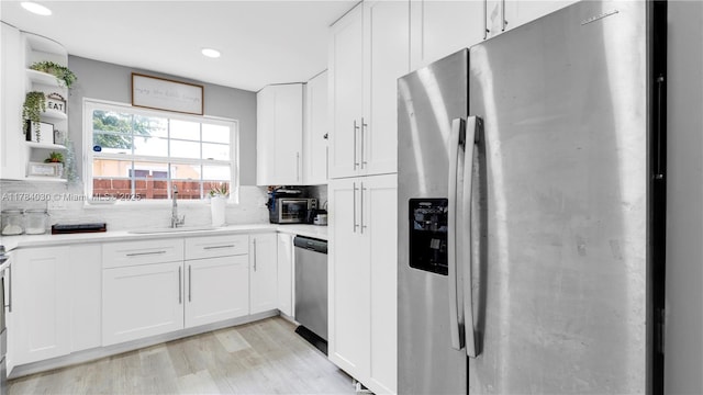 kitchen featuring decorative backsplash, stainless steel appliances, light countertops, a sink, and white cabinetry