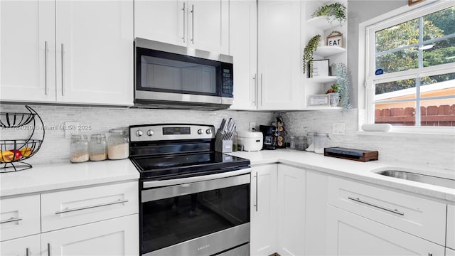 kitchen featuring light stone counters, decorative backsplash, stainless steel appliances, open shelves, and white cabinets