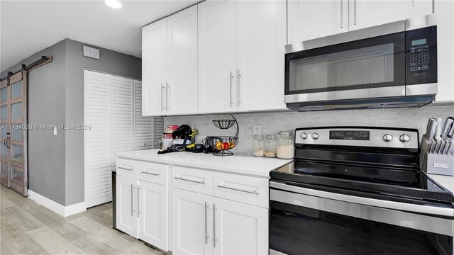 6582 SW 20th St, North Lauderdale, FL 33068 - kitchen with stainless steel appliances, a barn door, light wood finished floors, white cabinets, and recessed lighting