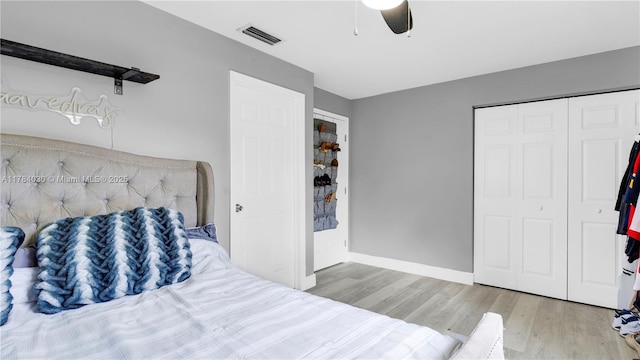 bedroom featuring wood finished floors, a closet, baseboards, visible vents, and a ceiling fan