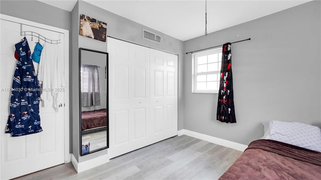 bedroom with visible vents, a closet, light wood finished floors, and baseboards