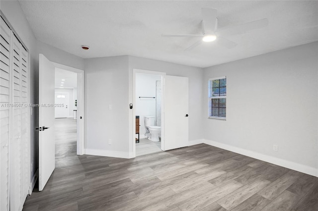 unfurnished bedroom with baseboards, ensuite bath, and wood finished floors