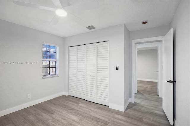 unfurnished bedroom with visible vents, a closet, baseboards, and wood finished floors