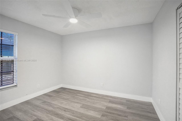unfurnished room featuring wood finished floors, baseboards, and a ceiling fan