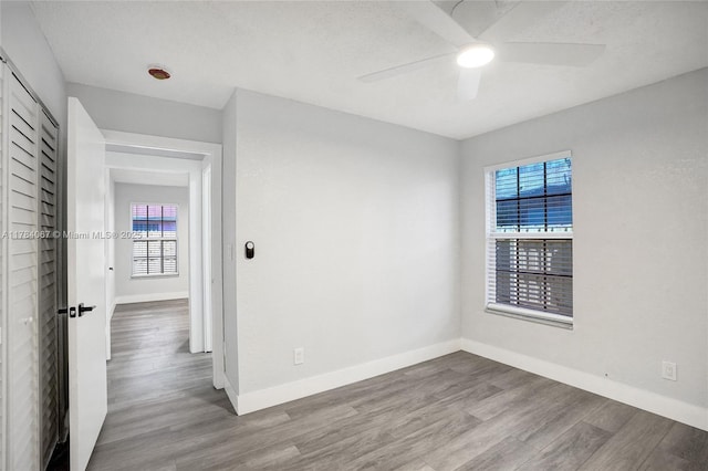 unfurnished room featuring plenty of natural light, baseboards, and wood finished floors