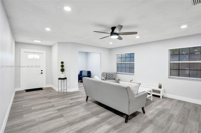 living room featuring light wood finished floors, baseboards, and ceiling fan