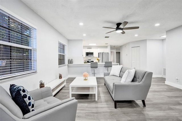 living area featuring visible vents, baseboards, light wood-type flooring, a ceiling fan, and recessed lighting